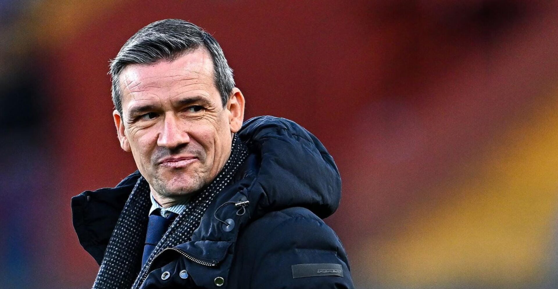 Marco Ottolini, ex ds del Genoa, in giacca e cravatta con alle spalle lo stadio Luigi Ferraris