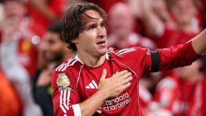 Chiesa esulta battendo la mano sullo stemma del Liverpool dopo un gol in Premier League