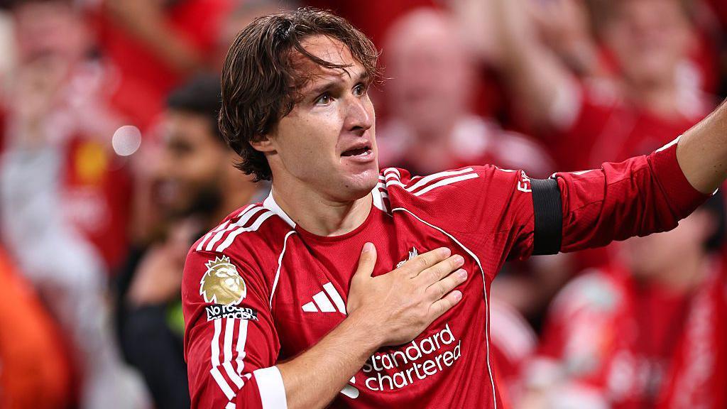 Chiesa esulta battendo la mano sullo stemma del Liverpool dopo un gol in Premier League